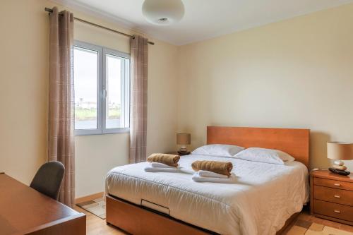 Un dormitorio con una cama con un escritorio y una ventana. en Costa's Guest House, en Algarvia
