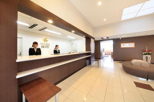 a lobby of a hotel with two people sitting at a counter at Vessel Hotel Higashi Hiroshima in Higashihiroshima