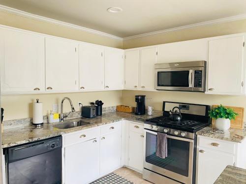 a kitchen with white cabinets and stainless steel appliances at 1 bedroom terrace view with shared bathroom #4 in Laurel