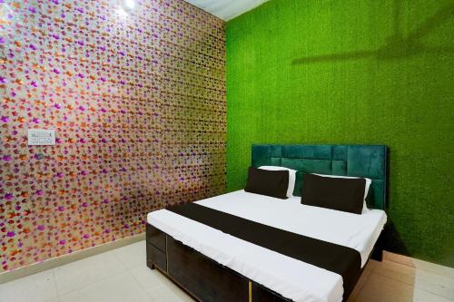 a bedroom with a bed with a green wall at SPOT ON GANGA HOTEL in Alīgarh