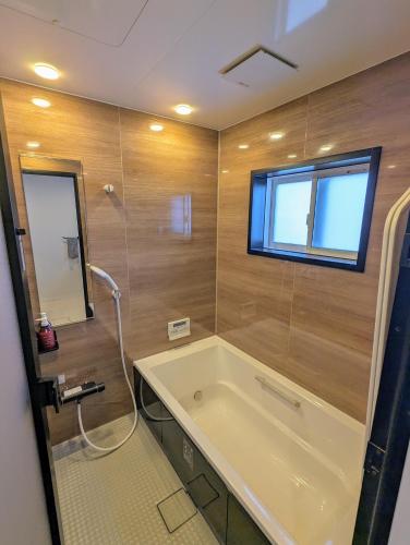 a bathroom with a bath tub and a window at Asuka Resort 富士山中湖 in Yamanakako