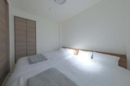 a bedroom with a white bed with a wooden headboard at Cozy Nest Nakano 2 stops 5 min to Ikebukuro 7 stops to Shinjuku 15 min new 1LDK in Tokyo