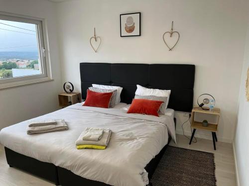 a bedroom with a large bed with red pillows and a window at Queen Villa - Santa Barbara - Lourinha in Santa Barbara