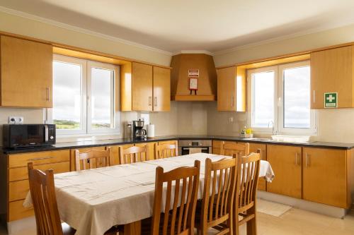 a kitchen with a table and chairs and windows at Costa's Guest House in Algarvia