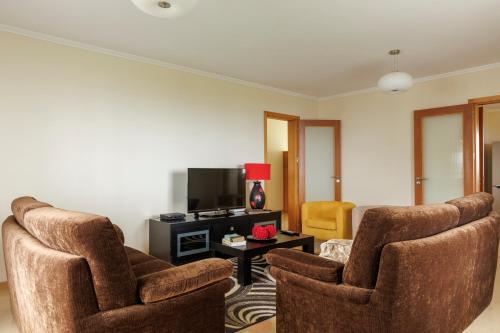 a living room with two chairs and a tv at Costa's Guest House in Algarvia