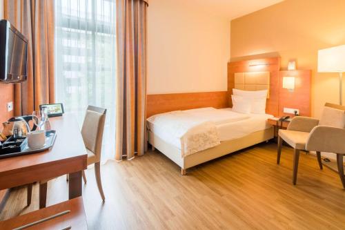 a hotel room with a bed and a desk at Best Western Plus Hotel Am Schlossberg in Nürtingen