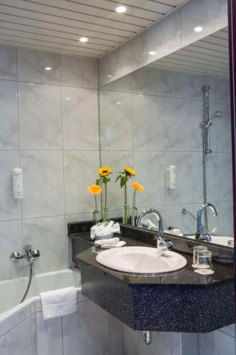 a bathroom with a sink and a tub and a mirror at Best Western Plus Hotel Am Schlossberg in Nürtingen
