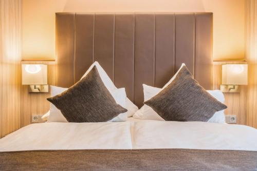a bedroom with a large bed with pillows at Best Western Plus Hotel Regence in Aachen