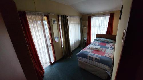 a bedroom with a bed and some windows at Casa los Villarroel in Ancud