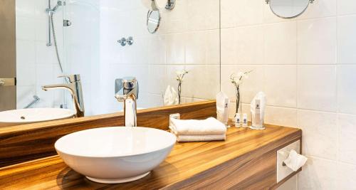 a bathroom with a bowl sink and a mirror at Best Western Victor's Residenz-Hotel Rodenhof in Saarbrücken