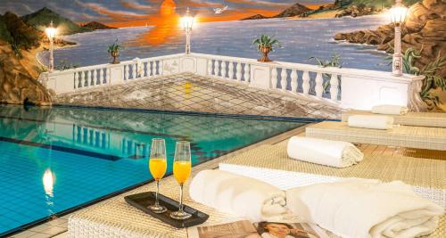 a hotel room with a swimming pool and two glasses of champagne at Best Western Victor's Residenz-Hotel Rodenhof in Saarbrücken