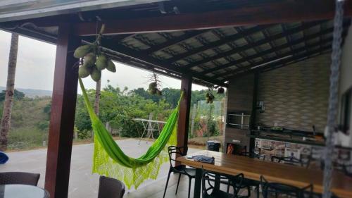 a room with a table and a hammock in a house at Rancho Bela Vista - Corumbá IV in Alexânia