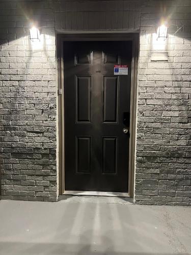 a black door with two lights on a brick wall at Queen Suite - Attached Bath - Home Theater - Home Tub in Forest Park