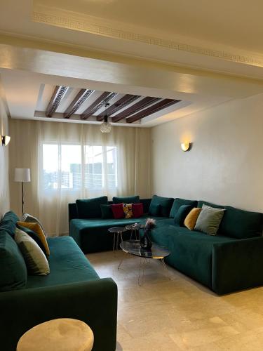 a living room with two green couches and a table at SUITOUISS - AGDAL 5 - Appartements à 2 minutes de la gare de train TGV Rabat in Rabat