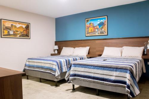 two beds in a hotel room with blue walls at Casa 080 in Guatemala