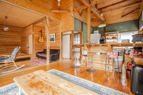 a living room with wooden walls and wooden floors at 新緑の南伊豆焚き火の宿ノキロ in Minamiizu
