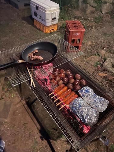 a grill with a pan and some food on it at 新緑の南伊豆焚き火の宿ノキロ in Minamiizu