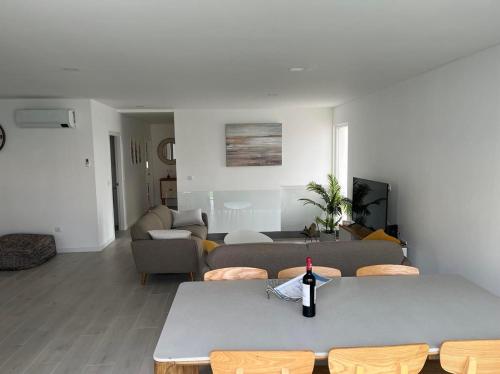 a living room with a table with a bottle of wine at Queen Villa - Santa Barbara - Lourinha in Mariquiteira