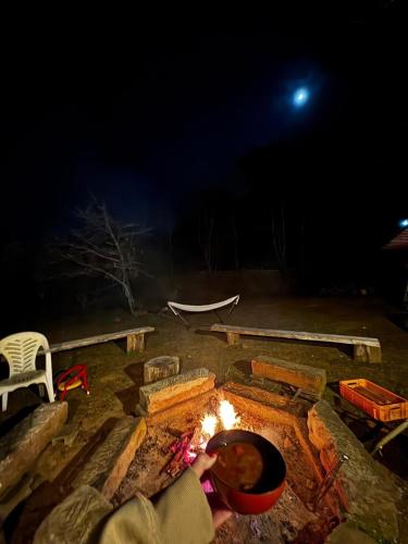 a person cooking food over a fire at night at 新緑の南伊豆焚き火の宿ノキロ in Minamiizu