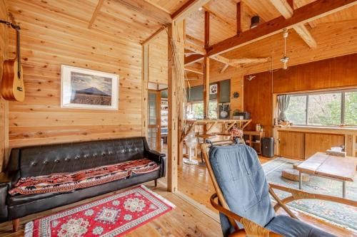 a living room with a leather couch in a log cabin at 新緑の南伊豆焚き火の宿ノキロ in Minamiizu