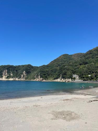 a view of a beach with mountains in the background at 新緑の南伊豆焚き火の宿ノキロ in Minamiizu