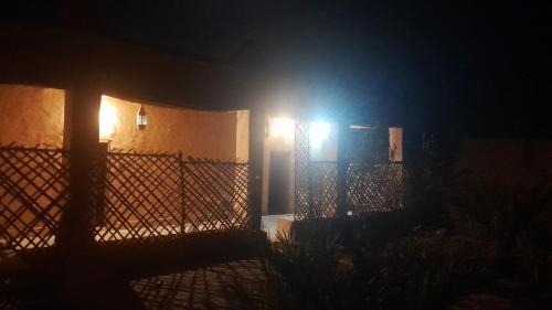a fence with lights on the side of a house at night at Dar Tamzdamte Skoura in Skoura
