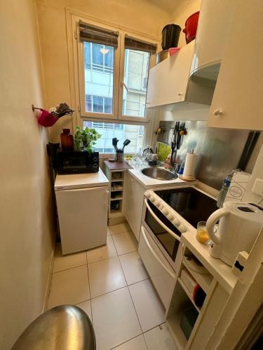 une cuisine avec des placards blancs et une grande fenêtre dans l'établissement Studio Étoile - Champs Élysées, à Paris