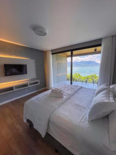 a bedroom with a large bed with a large window at Mansão VOAR in Florianópolis