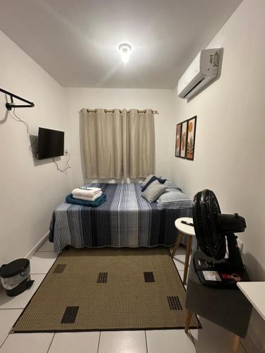 a bedroom with a bed and a table with a fan at Cantinho Aconhegante - Quarto 06 AR-condicionado in Bayeux