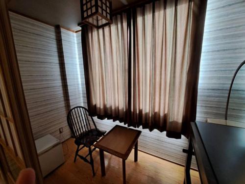 a chair and a table in front of a window at Business Hotel Kawakami in Kumano