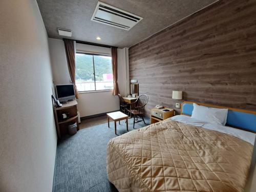 a hotel room with a bed and a desk and a window at Business Hotel Kawakami in Kumano