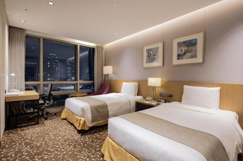a hotel room with two beds and a desk at Holiday Inn Incheon Songdo by IHG in Incheon
