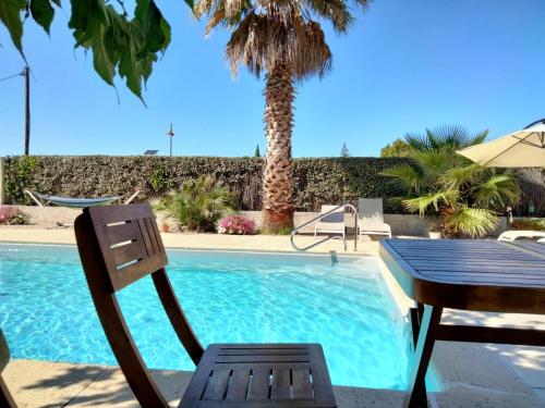 - une table et une chaise à côté de la piscine dans l'établissement Les Platanes, à LʼIsle-sur-la-Sorgue