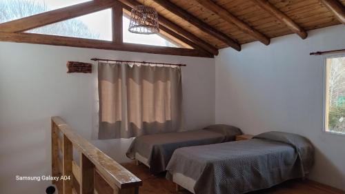 a bedroom with two beds and a window at Alojamiento Küme Kiyen in Aluminé