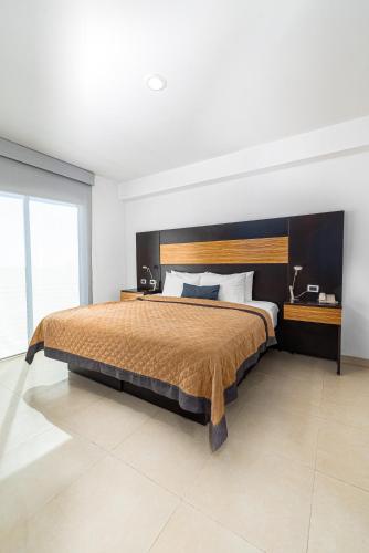 a bedroom with a large bed with a wooden headboard at Hotel México Plaza Silao Aeropuerto in Silao