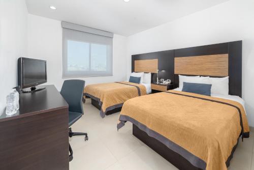 a hotel room with two beds and a flat screen tv at Hotel México Plaza Silao Aeropuerto in Silao