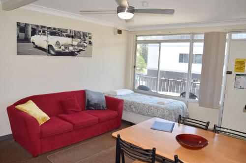 a living room with a red couch and a table at Wards Holiday Flat 7 in South West Rocks