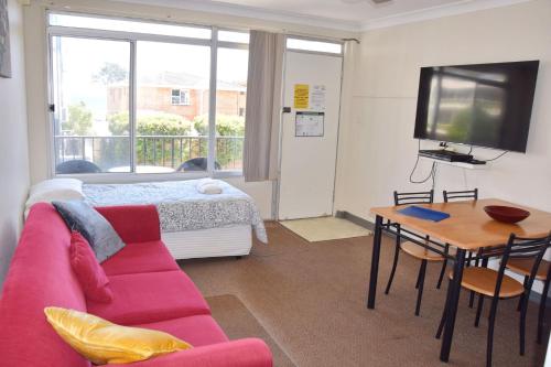 a living room with a couch and a table and a tv at Wards Holiday Flat 7 in South West Rocks