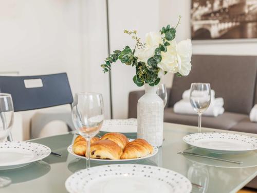 une table avec des assiettes de croissants et un vase avec des fleurs dans l'établissement Lovely studio near Eiffel Tower, à Paris