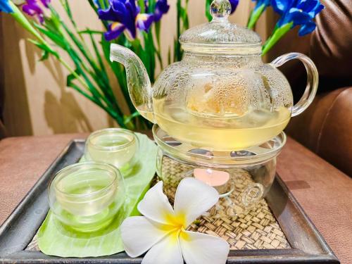 a tea pot on a tray with flowers and candles at The Yama Hotel Phuket in Kata Beach