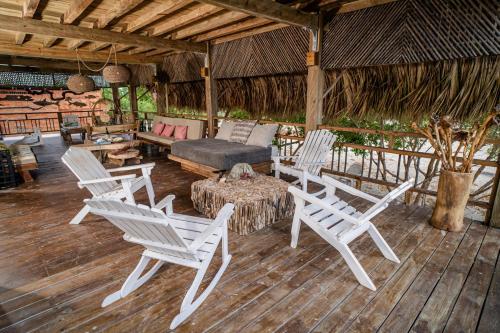 a porch with white chairs and a bed and a table at Casa del Mar by Al Alma in San Onofre