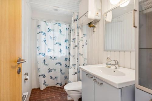 Un baño con lavabo, inodoro y cortina de ducha. en Cozy House On Mols With A View Of The Sea, en Knebel