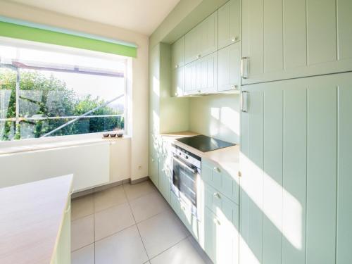 a kitchen with green cabinets and a window at Stylish Retreat with Sauna in Awenne