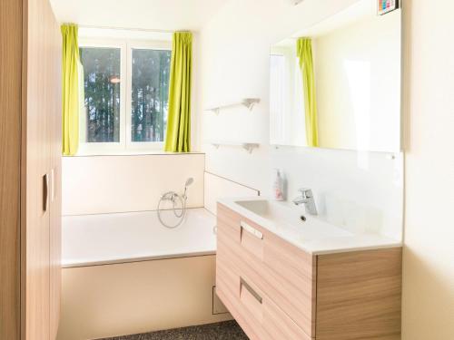 a bathroom with a sink and a tub and a window at Stylish Retreat with Sauna in Awenne