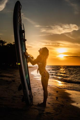 a woman standing on the beach holding a surfboard at Casa del Mar by Al Alma in San Onofre