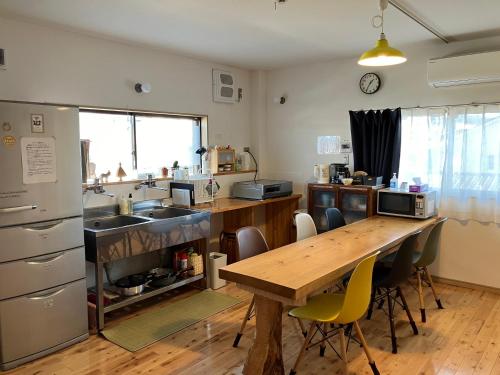 a kitchen with a wooden table and a kitchen with a sink at Shioya Hostel in Akune