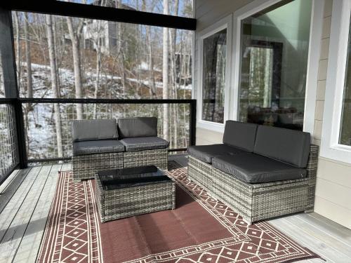a screened in porch with two chairs and a table at Seven Bears in the Woods -Modern-Luxury-Cabin--Hot Tub-Game Room in Sevierville