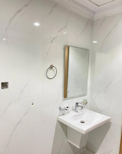 a white bathroom with a sink and a mirror at كويت سفن للشقق المخدومة in Jeddah