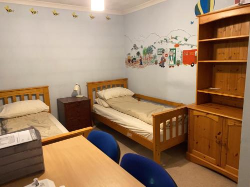 a room with two beds and a desk and a table at Bickley London Holiday Home in Bromley