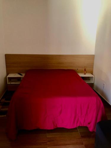 una camera da letto con un letto rosso con due tavoli di Aconchego a Maceió